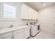 Laundry room boasts white cabinets, countertop, sink, and modern appliances at 12295 Skyracer Dr, Las Vegas, NV 89138