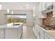 Modern kitchen with white cabinets, stainless appliances, an island, tile backsplash, and sliding door backyard access at 12550 Point Sierra St, Las Vegas, NV 89138