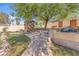 Lush backyard featuring a stone walkway, pergola, greenhouse, and mature trees at 1795 Nuevo Rd, Henderson, NV 89014