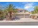 Inviting two-story home featuring a three-car garage, desert landscaping and a mature palm tree in front at 1795 Nuevo Rd, Henderson, NV 89014