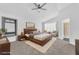 Bright bedroom featuring a wood bed frame, a ceiling fan, sitting chairs, and a bathroom entrance at 1795 Nuevo Rd, Henderson, NV 89014