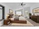 Bright bedroom featuring a wood bed frame, a ceiling fan, sitting chairs, and a bathroom entrance at 1795 Nuevo Rd, Henderson, NV 89014