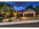Charming home exterior with a three-car garage, desert landscaping, and illuminated entrance at 2786 Scotts Valley Dr, Henderson, NV 89052