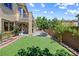 A lush backyard features artificial grass, mature trees and plants, a small patio, and a brick perimeter at 3405 Brook Song Ave, North Las Vegas, NV 89081