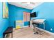 Bright bedroom in blue with a ceiling fan, mounted TV, and desk, plus drawers and art at 3405 Brook Song Ave, North Las Vegas, NV 89081