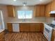 Open kitchen with wood-look laminate floors, wood cabinetry, and white appliances at 5316 Fireside Ranch Ave, Las Vegas, NV 89131
