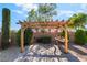 Beautiful outdoor pergola area with pavers, seating, and manicured shrubs at 5601 Mackenzie Park Ct, Las Vegas, NV 89130