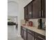 Adjacent butler's pantry with dark wood cabinetry, granite counters, and a view into the open living area at 7230 Fresh Harvest Ave, Las Vegas, NV 89131