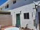 Rear exterior view featuring a green door, small patio, and white stucco at 745 Greenbriar Townhouse Way, Las Vegas, NV 89121