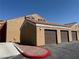 Exterior of a multi-car garage with stucco exterior, tile roof and red rock landscaping at 8101 W Flamingo Rd # 1044, Las Vegas, NV 89147