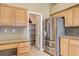 Kitchen featuring stainless steel fridge, pantry, granite countertops, and wooden cabinetry at 8204 Turbys Treehouse Pl, Las Vegas, NV 89131