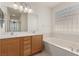 Main bathroom featuring double sinks, soaking tub, and privacy windows at 10463 Luna Magico Ave, Las Vegas, NV 89135