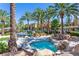 Community pool and spa area with palm trees, waterfall features, and lounge chairs at 10640 Amber Ridge Dr # 101, Las Vegas, NV 89144
