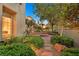 Serene backyard with a stone fire pit, lush greenery, and gravel pathways at 1404 Reisling Ct, Las Vegas, NV 89144