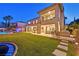 Evening view of the backyard showcasing the pool, outdoor dining, and spacious lawn at 1404 Reisling Ct, Las Vegas, NV 89144