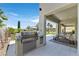 Outdoor kitchen area with a built-in grill, dining space, and a view of the lush backyard at 1404 Reisling Ct, Las Vegas, NV 89144