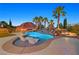 Backyard pool with a waterfall and in-water lounge chairs under a tiki umbrella, all beautifully lit at dusk at 1404 Reisling Ct, Las Vegas, NV 89144
