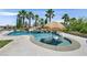 Backyard pool features a small waterfall and two submerged lounge chairs with a tiki umbrella for relaxing in the sun at 1404 Reisling Ct, Las Vegas, NV 89144