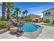 Lush pool area with a rock waterfall feature, palm trees, and a cozy cabana with lounge chairs at 1404 Reisling Ct, Las Vegas, NV 89144