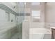 This bathroom features a glass shower, a white tub, and neutral-toned tile with decorative inlays at 1761 Summerwood Cir, Henderson, NV 89012