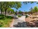 Community playground with slides and swings surrounded by mature trees, grassy areas, and walking paths at 1761 Summerwood Cir, Henderson, NV 89012