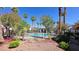 Community pool surrounded by trees and flowers, enhanced by sunny skies and tropical palms at 2615 W Gary Ave # 2061, Las Vegas, NV 89123