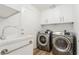 Bright laundry room with stainless steel washer and dryer, white cabinets, and a utility sink at 2920 Sterling Cove Dr, Las Vegas, NV 89128