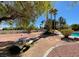 Expansive backyard featuring desert landscaping, mature trees, a pool, and an outdoor dining area at 4542 Amber Canyon Ln, Las Vegas, NV 89129