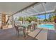 Covered patio with dining table, BBQ, and sparkling pool beyond at 4542 Amber Canyon Ln, Las Vegas, NV 89129