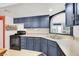 Kitchen featuring navy cabinets, modern appliances, neutral countertops and double stainless steel sink at 5008 Donnie Ave, Las Vegas, NV 89130