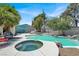 Backyard area with a pool, jacuzzi, lounge area, and mature trees, creating a perfect setting for outdoor relaxation and entertainment at 5008 Donnie Ave, Las Vegas, NV 89130