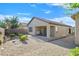 A beautiful desert landscaped backyard featuring gravel, shrubs, and a covered patio with a grill and outdoor seating at 6141 Tokara Ave, Las Vegas, NV 89122