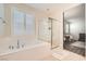 Bathroom featuring a soaking tub with jets, a clear glass shower, and plantation shutters on the window at 6233 Canterbury Field Rd, Las Vegas, NV 89113
