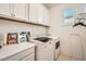 Well-lit laundry room with white cabinets, modern washer and dryer, and convenient counter space at 6233 Canterbury Field Rd, Las Vegas, NV 89113