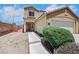Tan two story home with a two car garage and desert landscaping at 6678 Crystal Run Ln, Las Vegas, NV 89122