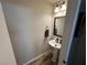 Powder room with pedestal sink, decorative mirror and hardwood flooring at 7226 Freedom Ring St, Las Vegas, NV 89148