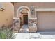 Close-up of home's entrance, showcasing stone accents, arched doorway, and well-maintained landscaping at 7407 Bakewell Ave, Las Vegas, NV 89179