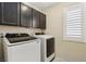 Bright laundry room with modern washer and dryer units and storage cabinets at 7407 Bakewell Ave, Las Vegas, NV 89179