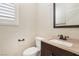 Elegant powder room featuring a vanity with granite countertop and dark wood cabinet, plus a toilet and window at 7407 Bakewell Ave, Las Vegas, NV 89179