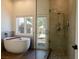 Primary bath featuring soaking tub, stylish glass enclosed shower, and view of an outdoor palapa at 7745 Radcliff St, Las Vegas, NV 89123