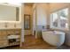 Bright bathroom features a soaking tub with shelf and a natural wood vanity at 7745 Radcliff St, Las Vegas, NV 89123