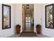 Inviting entryway featuring a decorative light fixture and wood flooring, framed by potted flowers and bright windows at 7745 Radcliff St, Las Vegas, NV 89123