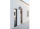 Exterior featuring a textured white wall, stylish light fixture, and access door at 7745 Radcliff St, Las Vegas, NV 89123