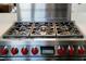 Close up of a stainless steel Wolf gas stove top with red knobs at 7745 Radcliff St, Las Vegas, NV 89123