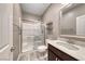 Bright bathroom features a glass-enclosed shower, wood-look tile floors and a modern vanity with marble countertops at 928 Riverlawn Pl, Las Vegas, NV 89138