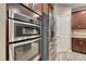 A stainless refrigerator and double oven set beside a door with matching cabinets at 928 Riverlawn Pl, Las Vegas, NV 89138