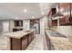 Open kitchen with dark cabinets, granite countertops, stainless appliances, and large island with sink at 928 Riverlawn Pl, Las Vegas, NV 89138
