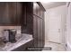 Kitchen area features dark wood cabinets, granite countertops and stainless appliances with a door to the laundry room at 10470 Irish Cliffs Ct, Las Vegas, NV 89149