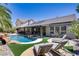 Spacious backyard with a pool, covered patio, lounge chairs, and lush landscaping at 1509 Winslow St, Las Vegas, NV 89117
