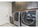 Laundry room featuring large washer and dryer, gray cabinets and a door to exterior at 1509 Winslow St, Las Vegas, NV 89117